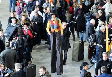 Man on stilts walking through crowd