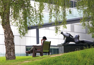 Man reading on bench, University of East Anglia