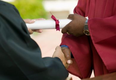 Man shaking hands and receiving university diploma