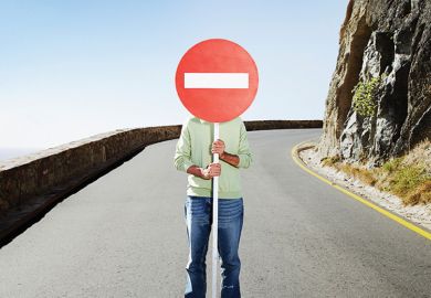 Man standing in road holding No Entry sign over face