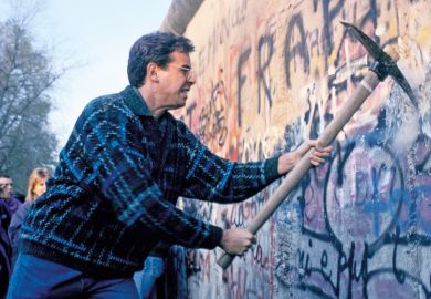 Man using pickaxe to break down Berlin Wall, 1989