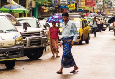 Man walking across congested street, Yangon, Myanmar