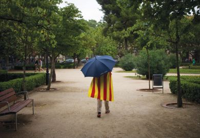 Man walks in rain wearing Catalan flag