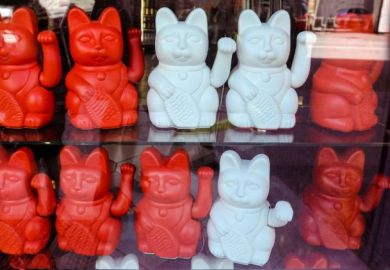 Maneki neko also known as chinese fortune cat. Showcase with welcoming souvenir cats beckoning to enter