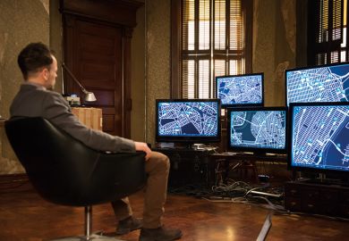 A man sitting in front of a bank of computer screens