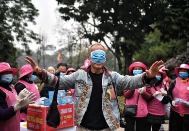 Man with medical mask covering his eyes surrounded by a crowd of people Man with medical mask over eyes surrounded by a crowd of people