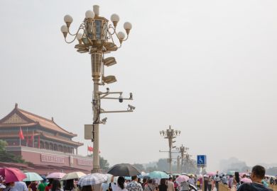 Mass tourists around the Tiananmen Gate Tower in a hot, hazy summer day in Beijing, China. Tourist attraction. Lamp post with surveillance cameras
