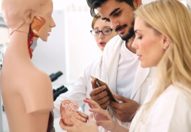 Medical trainees hold an anatomical dummy's brain, symbolising reorganising the NHS