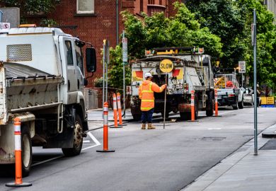Melbourne, Victoria, Australia, October 23rd, 2021 A traffic control worker is holding a SLOW sign to slow the traffic at an inner-city construction site
