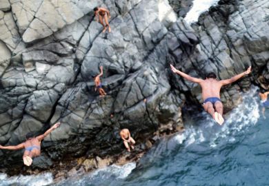Men diving off cliff into sea