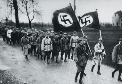 Men marching behind flags with swastikas on them