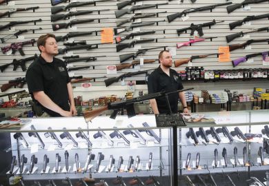 Men stand in front of display of firearms in gun store, Lake Barrington, Illinois