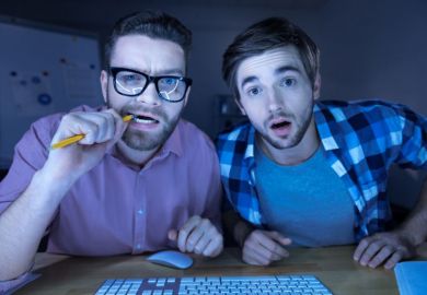 Men peering confused into computer screen