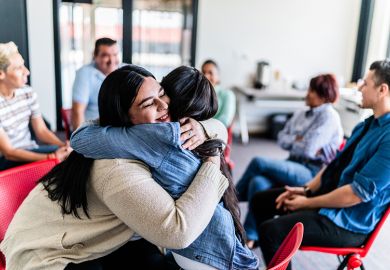 Women embracing during a group mental health session, to illustrate supporting staff mental health at universities.