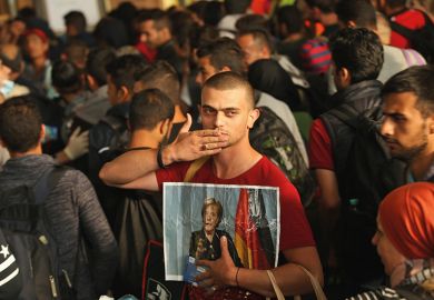 A migrant from Syria holds a picture of Angela Merkel A migrant from Syria holds a picture of Angela Merkel