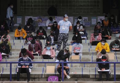 A staff member oversees students taking their UNAM admission exam while following the measures to avoid Covid-19 at Olimpico Universitario Stadium on August 19, 2020 in Mexico City,