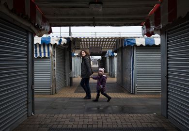 A woman and child walk through a market area with closed stalls in Milton Keynes, England.