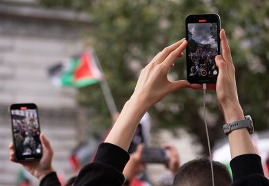 Protesters using phones to film a protest about the Israel-Gaza conflict. To illustrate students being fearful after the Trump administration’s proposal to vet all international students’ social media.