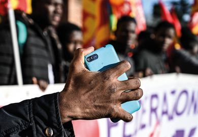 A migrant holds his mobile phone as members of anti-racism associations and migrants gather on Piazza della Repubblica in central Rome in December 2018 to protest the government’s decree restricting the right to asylum
