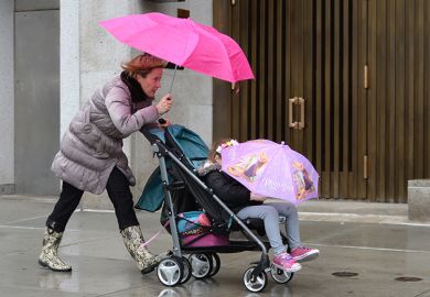 A mother pushing a child in a pushchair with the child concealed by an umbrella