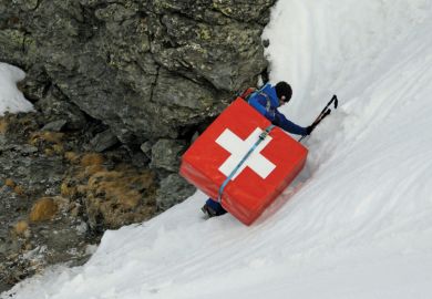 Mountain climber carrying safety mattress bearing Swiss flag