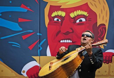 Man plays guitar in front of Donald Trump image