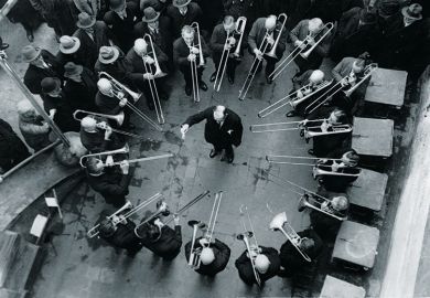 Musicians playing trombones around conductor
