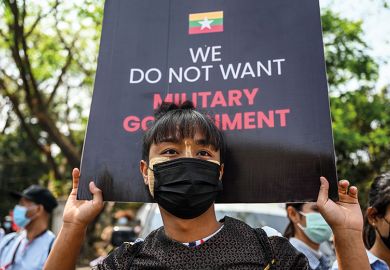 A man carries a sign during a protest next to Yangon University against the military coup in Yangon on February 25, 2021.