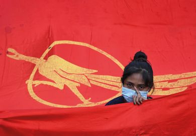 A protester stands with a Myanmar Student Union flag, 2021