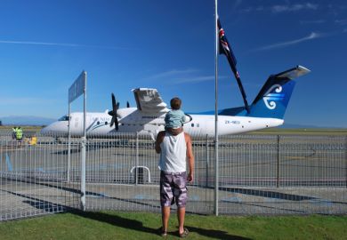 Nelson, New Zealand - March 10, 2012. A Man with a Boy on his shoulders look out to an Air New Zealand Aeroplane at Nelson's Domestic Airport, Nelson Region, New Zealand.