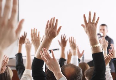 People raise their hands in a meeting, illustrating no-confidence votes