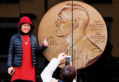 An Asian woman poses for a picture at the entrance of the Alfred Nobel Museum in Stockholm, Sweden, 2019. 