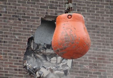 Orange wrecking ball demolishing building wall