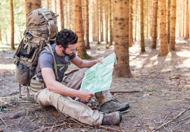 Outdoorsman/hiker sitting and reading map