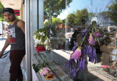 Flowers fill bullet holes in the windows of the IV Deli on May 25, 2014 in Isla Vista, California, after Elliot Rodger’s murderous rampage