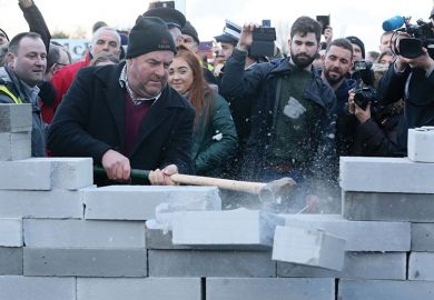 Protesters smash through mock wall
