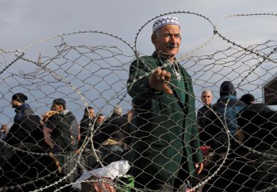 Palestinian man standing behind barbed fence, Gaza Strip, 2014