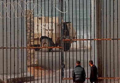 Displaced Palestinian men watch as an Egyptian army armoured personnel carrier drives near border fence between Gaza and Egypt in Rafah, in the southern Gaza Strip, amid the ongoing conflict between Israel and Hamas.