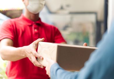 A parcel A shopworker hands over a brown parcel to a customer