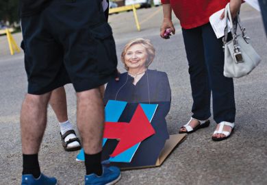 People looking at cardboard cutout of Hillary Clinton lying on road People looking at cardboard cutout of Hillary Clinton lying on road