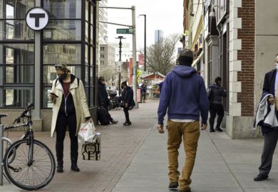 People pass each other on a non crowded street in Cambridge, MA during COVID-19 wearing face mask.