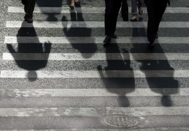 People's shadows cast on road crossing People's shadows cast on road crossing