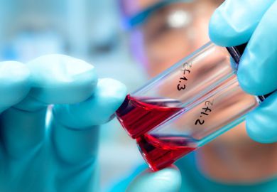 Person holding blood samples in test tubes