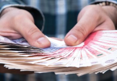 Person holding large fan of British currency in hands