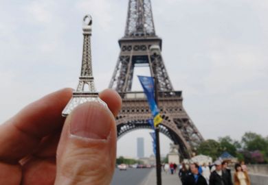 Person holding model in front of Eiffel Tower, Paris, France