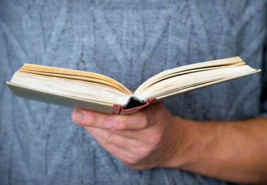 Person holding open book in hand