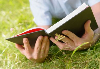 Person lying on grass reading book