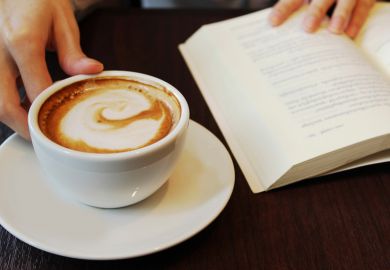 Person reading and drinking coffee