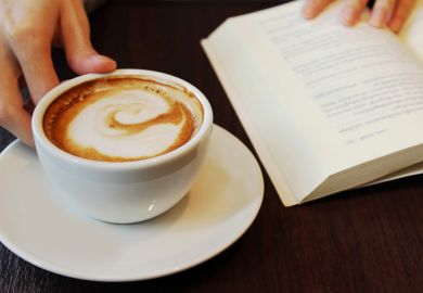 Person reading book and drinking coffee