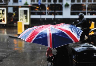 Person walking in rain carrying Union Jack umbrella Person walking in rain carrying Union Jack umbrella